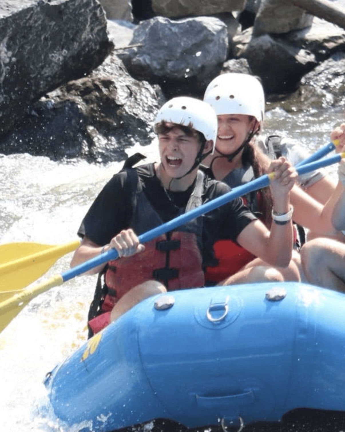 Jeffrey paddling hard through whitewater rapids on a raft