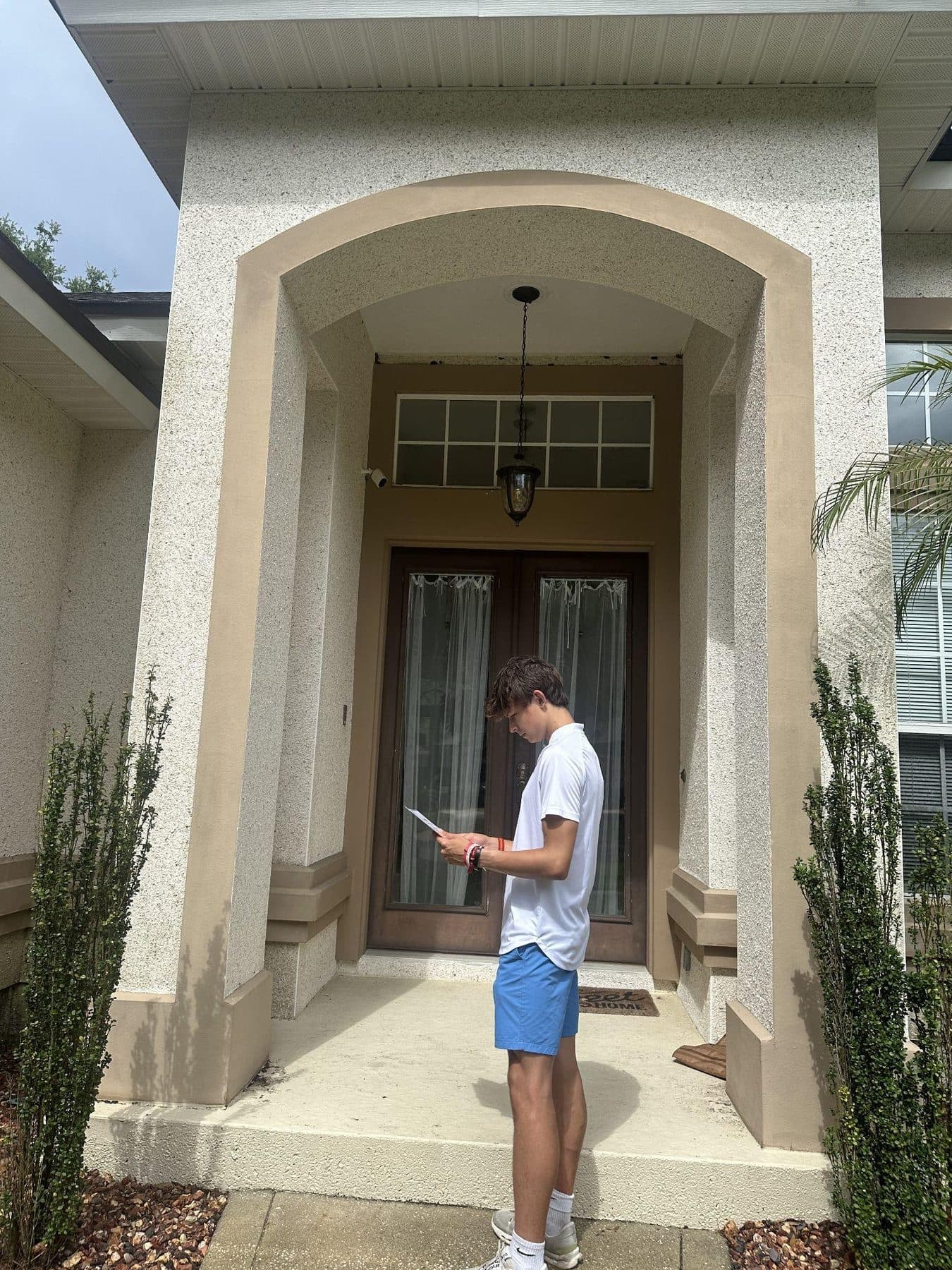 Jeffrey reading his notes on a front porch before knocking on the door