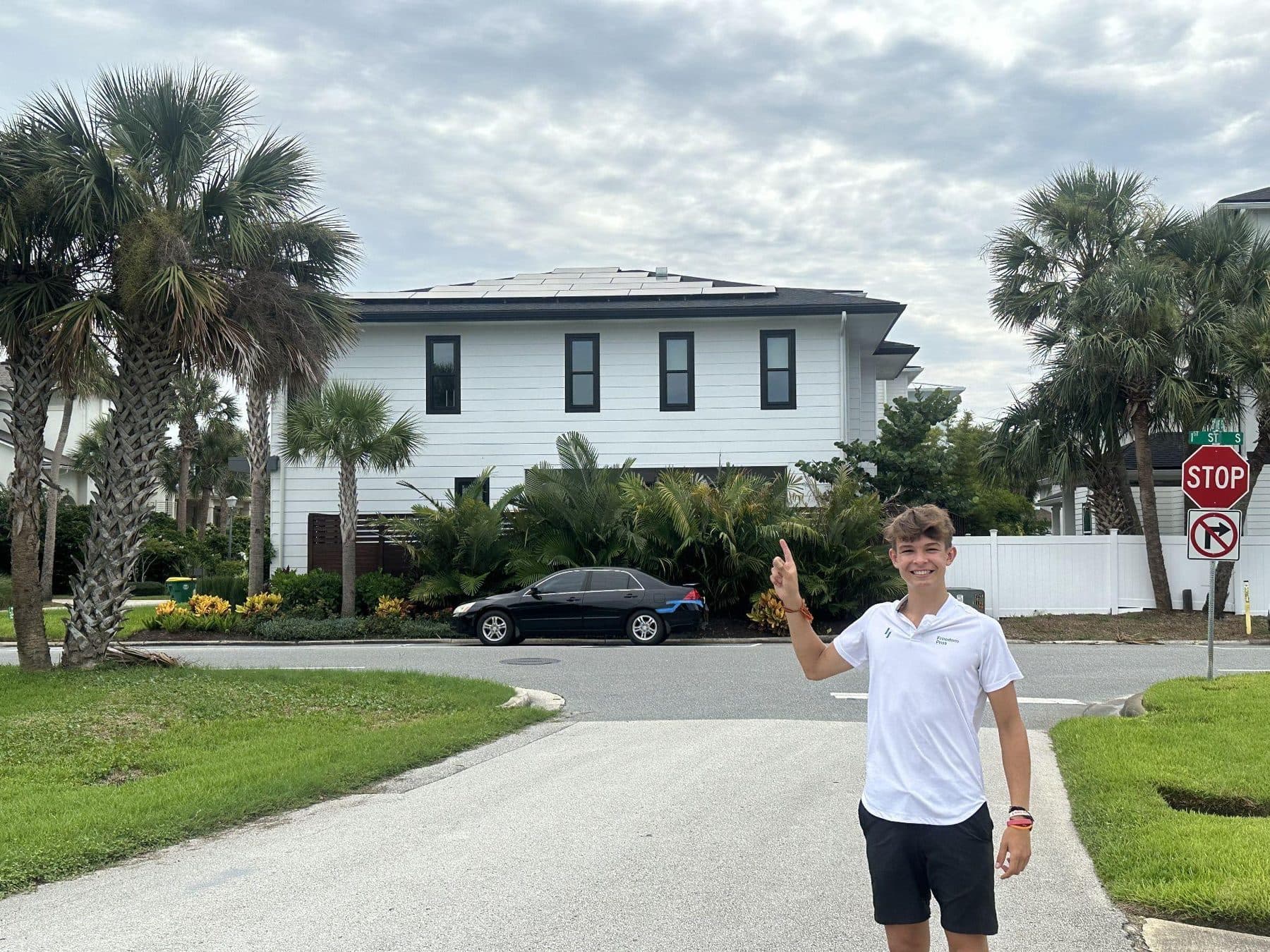 Jeffrey on a palm-lined Florida street in front of a house with rooftop solar
