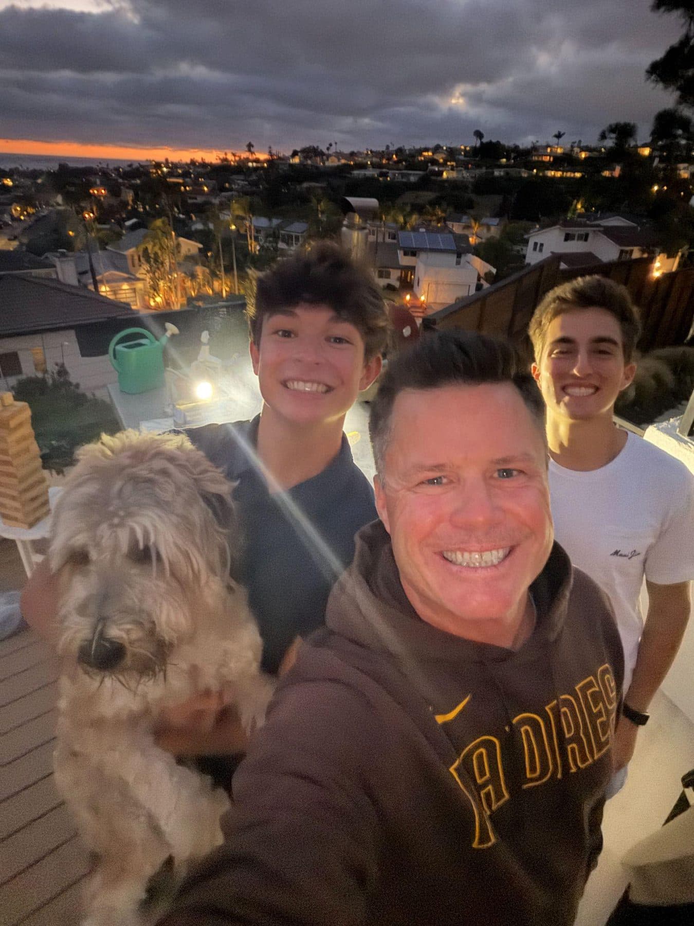 The Skip The Groomer team on a rooftop at sunset with a dog