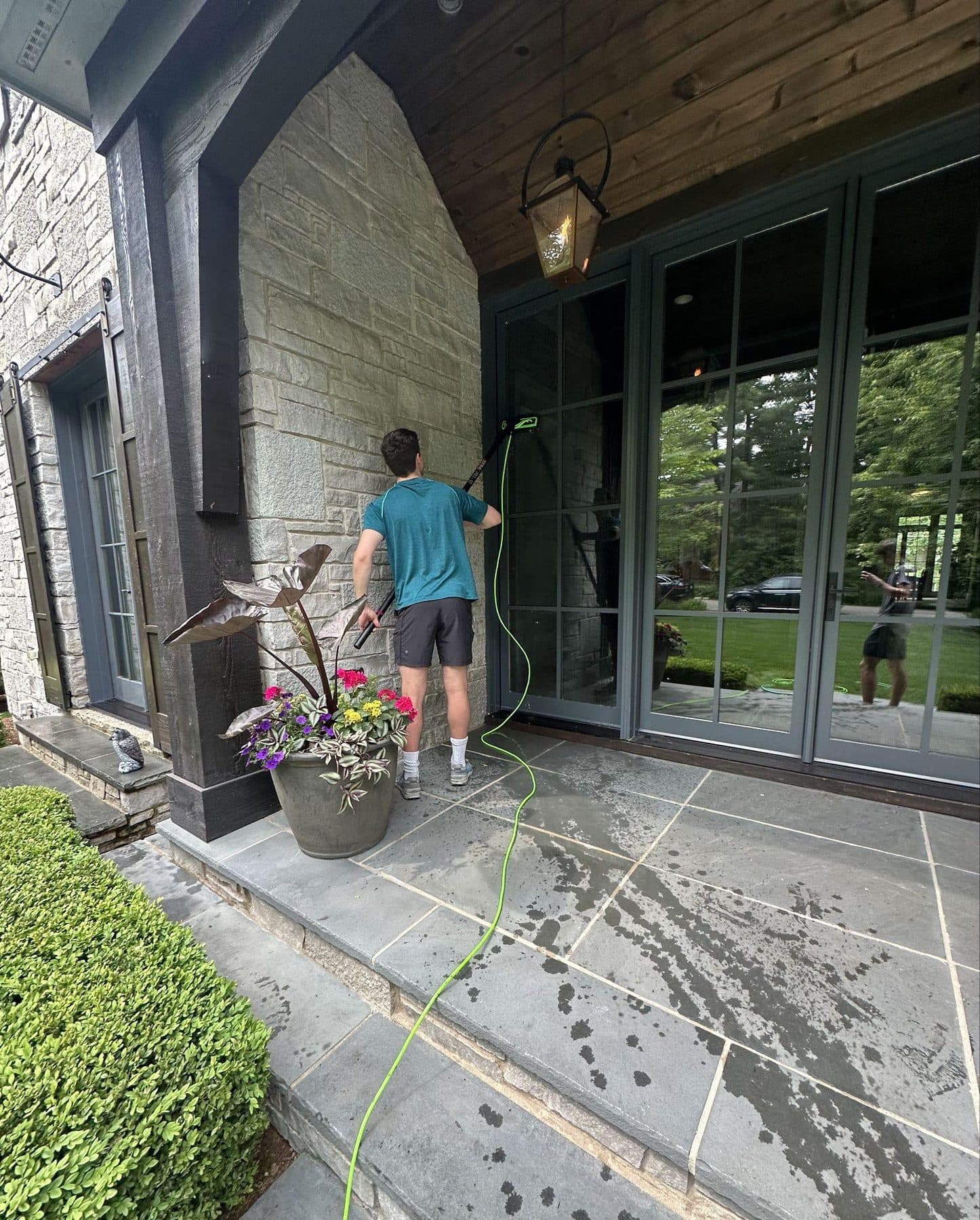Washing tall patio doors at the back of a stone house